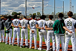 Baseball players saluting the flag during the National Anthem.